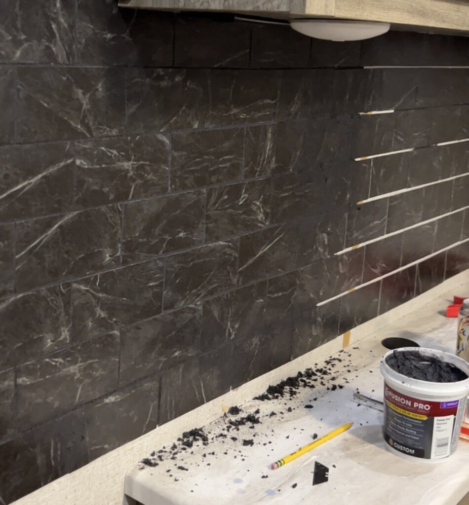 Black vinyl tile being grouted with black grout