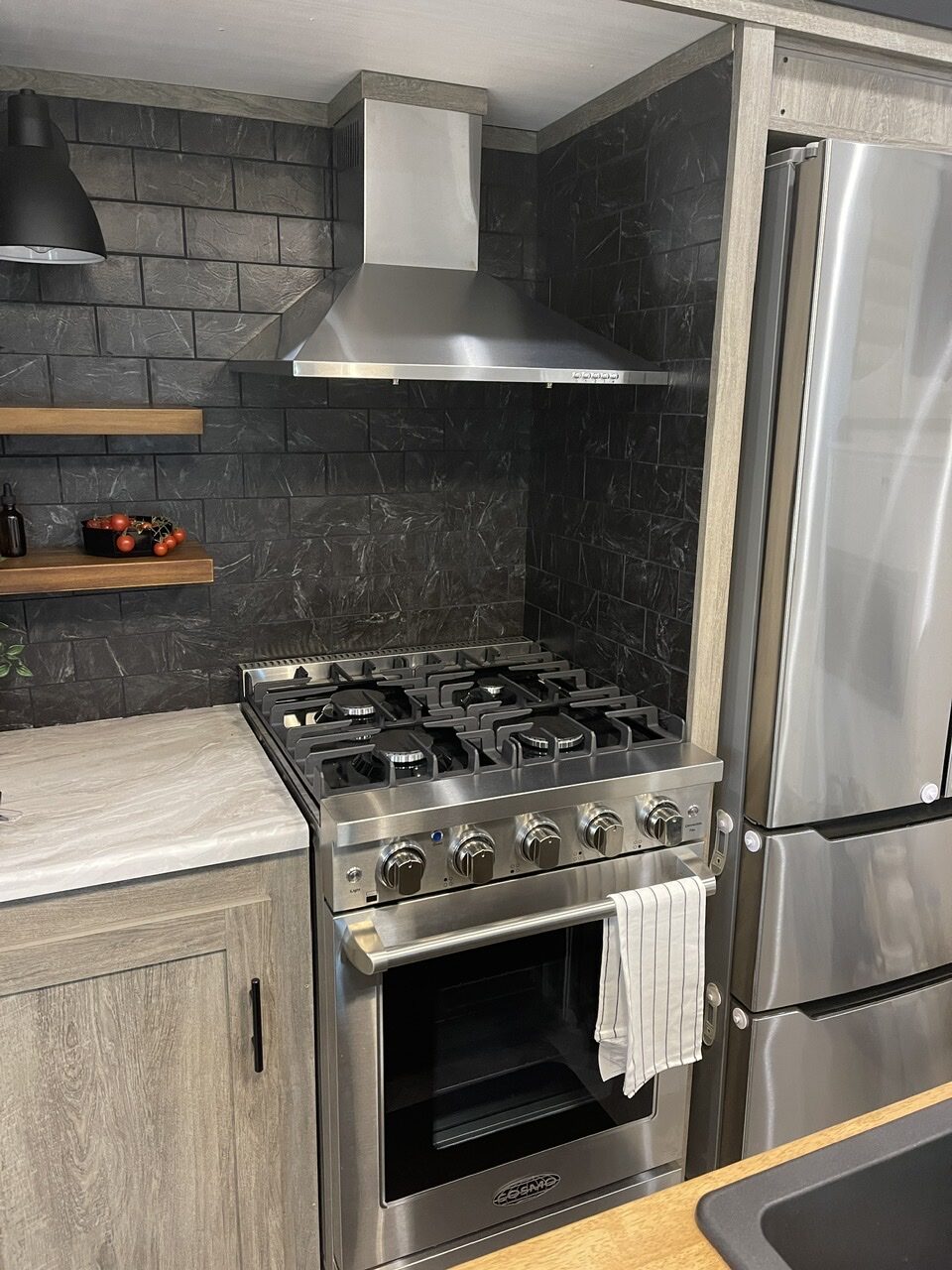 Fully renovated rv kitchen with modern black marble backsplash and stainless steel appliances 