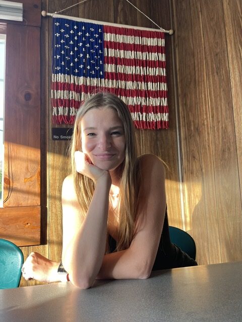 beaded American flag tapestry, warm light on a smiling woman